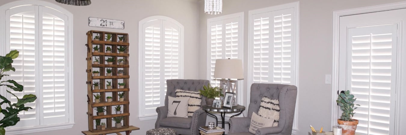 sitting area with grey chairs and white interior shutters.